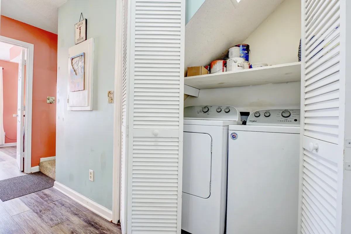 A laundry area with a washer and dryer, colorful walls, and a doorway leading to other rooms. The mood is casual and practical, highlighting essential amenities for a family’s convenience during their stay.