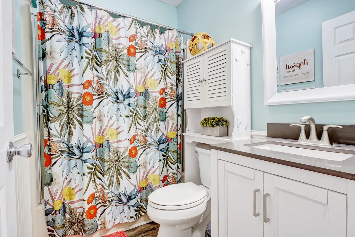A cheerful bathroom featuring a colorful shower curtain, a bright vanity unit, and decorative accessories. The space is well-lit and inviting, making it ideal for families to share.